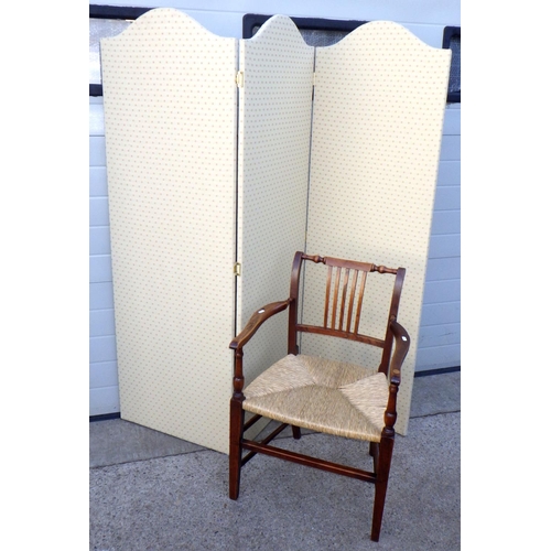 915 - An upholstered three panel screen together with a rush seat carver chair (a/f) (2)