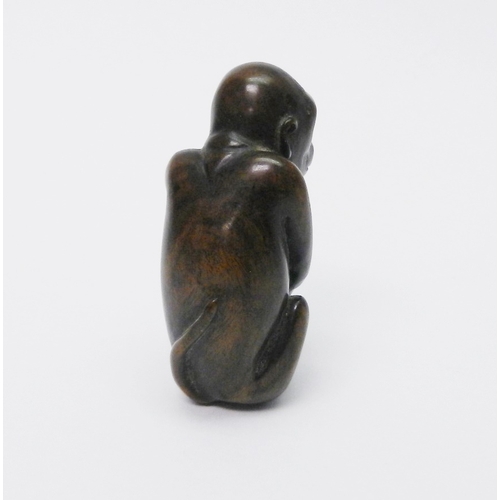 105 - An okimono depicting a seated monkey, carved hardwood, 50mm tall