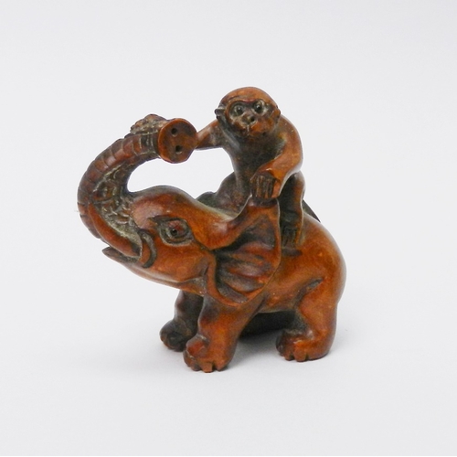 106 - An oriental okimono carved as a monkey sitting on an elephant,  57mm tall.