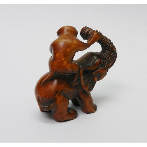 106 - An oriental okimono carved as a monkey sitting on an elephant,  57mm tall.