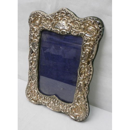 15 - An Edwardian silver repousse fronted photograph frame, a/f, aperture 135x90mm; a continental white m... 