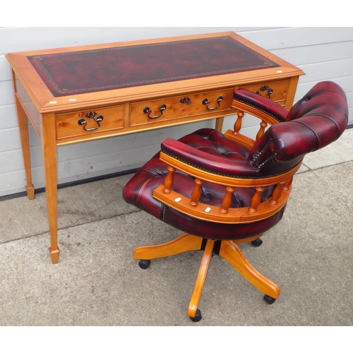 A reproduction writing table with red leather inset top, 122cm wide, together with a matching button leather swivel chair (2)