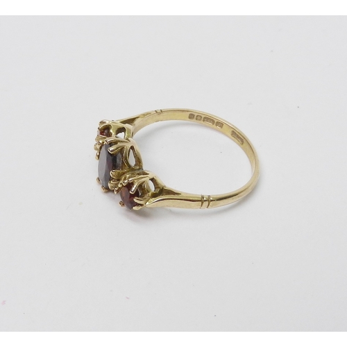 33 - A trilogy ring comprising oval cut garnets in a 9ct gold claw setting, late 20th cent.  1.5g / centr... 