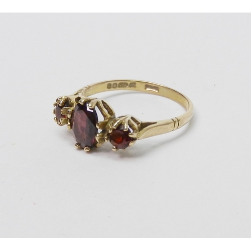 33 - A trilogy ring comprising oval cut garnets in a 9ct gold claw setting, late 20th cent.  1.5g / centr... 