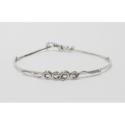 A bangle of part articulated design having a central applied twist / loop motif, platinum bearing Sheffield mark CSJ.  9.5g / 60mm across