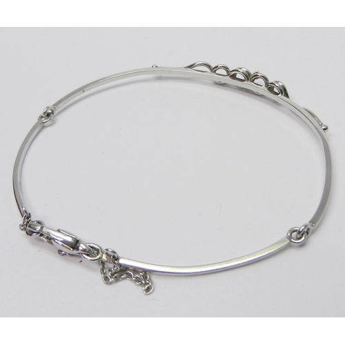 34 - A bangle of part articulated design having a central applied twist / loop motif, platinum bearing Sh... 