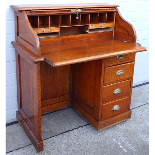 514 - A 1930's oak roll top desk with tambour top and brass handles, 102cm wide