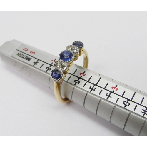 A diamond and sapphire eternity ring, comprising three graduated sapphires and four illusion set rose cut diamonds in pairs, the shank marked 18ct.  Size P / central stone approx 3.5mm diameter.