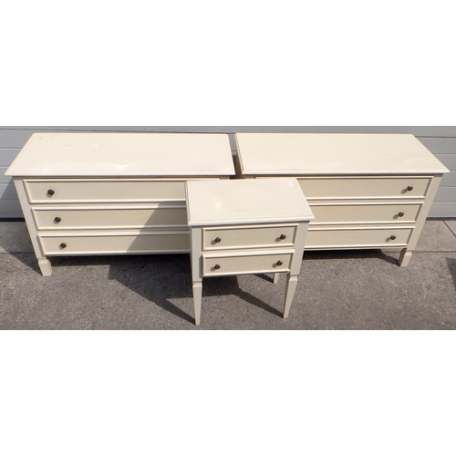A pair of cream painted chest's of drawers, 110cm wide together with a matching bedside table (3)