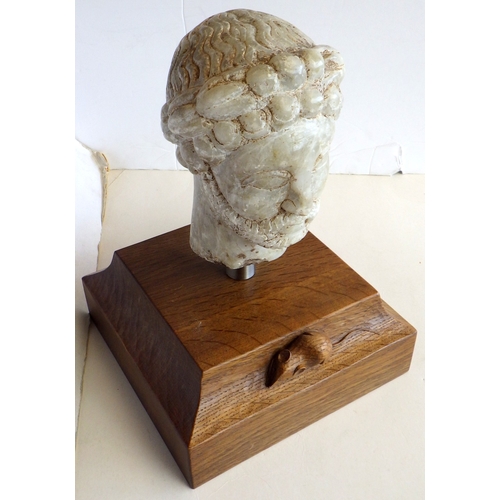 A Syrian carved stone head mounted on a Workshop of Robert Mouseman Thompson (Kilburn) oak plinth with carved mouse trademark, 32cm tall incl base,, base is 22cm square