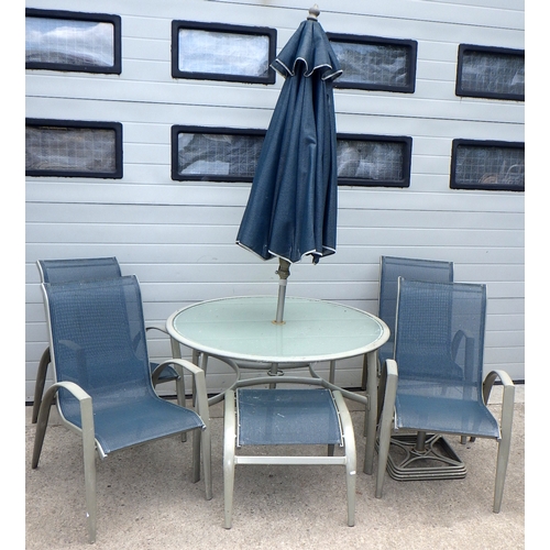 678 - An aluminum framed glass topped circular garden table with umbrella, base, four stacking chairs & fo... 