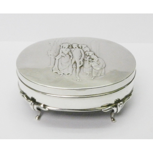 An Edwardian silver repousse jewellery / ring box standing on four scroll feet, the cover depicting a wedding scene, William Comyns London 1906.  155 x 78mm oval