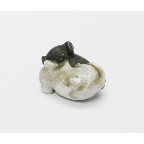 A Japanese porcelain netsuke depicting two puppies fighting.  Approx 35mm long