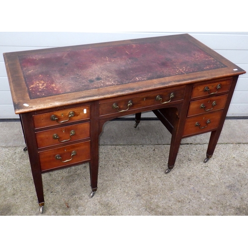 608 - An Edwardian mahogany kneehole desk with red leather inset top, on brass castors, 130cm wide