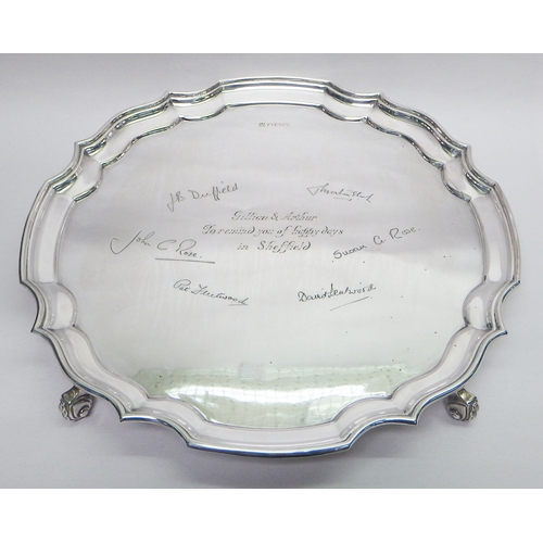 22 - A silver presentation salver standing on four scroll feet, Sheffield 1946.  305mm diameter / 840g