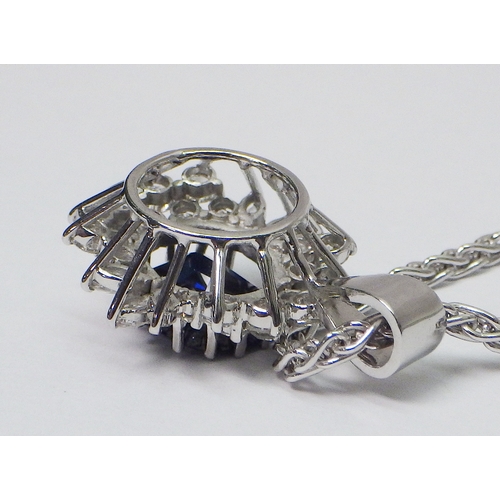 31 - A cluster pendant comprising an oval sapphire surrounded by 28 diamonds of round an marquise cuts, u... 