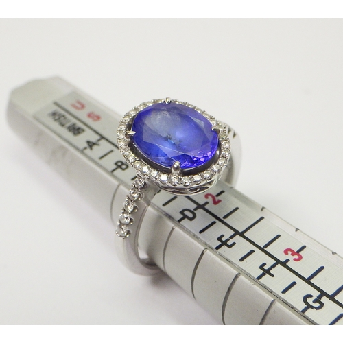 40 - A tanzanite and diamond halo ring in a white metal setting marked 750 / 18k.  Central stone approx 8... 