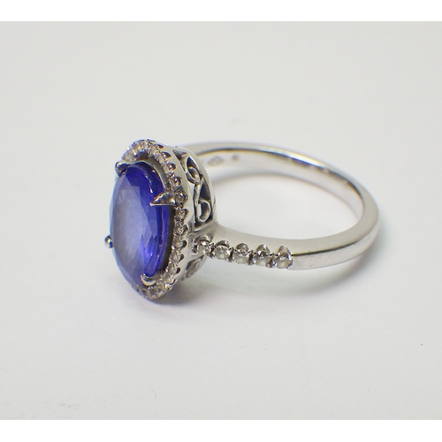 40 - A tanzanite and diamond halo ring in a white metal setting marked 750 / 18k.  Central stone approx 8... 