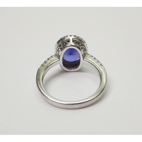 40 - A tanzanite and diamond halo ring in a white metal setting marked 750 / 18k.  Central stone approx 8... 