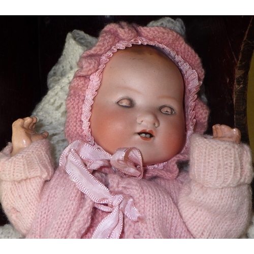 54 - An Armand Marseille doll in a pine crib together with a 20thC bisque doll in a wicker crib (2)