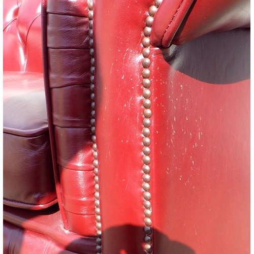 613 - A red button upholstered leather two seater Chesterfield sofa, cat scratches, 148cm wide