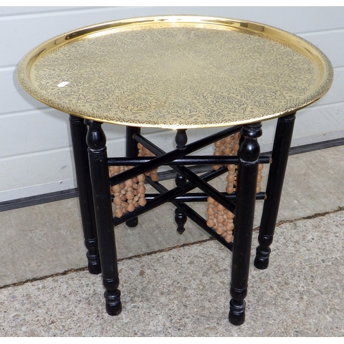 681 - A brass topped Benares table on folding ebonised base, 59cm across