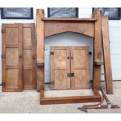 An Adzed oak fire surround with hanging kettle bracket and four carved oak doors
