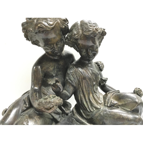 1040 - A heavy bronze figural group bronze of a boy and girl seated upon rocks. 30 x 38cm.