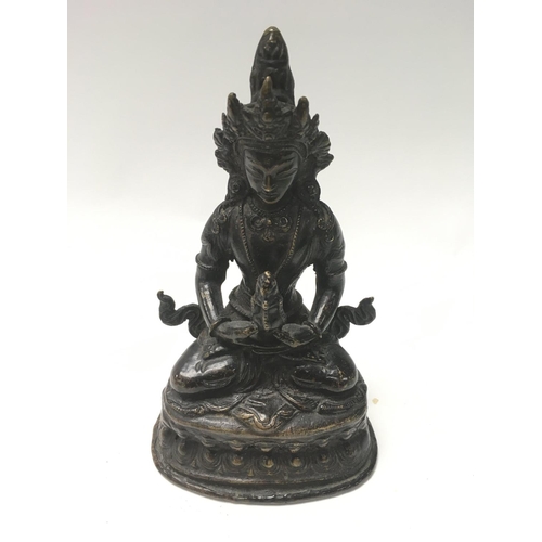 1306 - A Tibetan bronze Figure of a seated Tara holding a flame. 18cm.