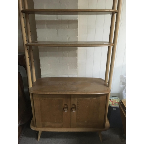 1364 - A Ercol open bookcase with three open selfs and cupboards under on turned legs height 190 cm .