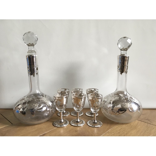 710 - Two antique liqueur decanters with silver overlay plus six matching glasses.