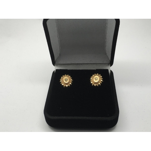 745 - A pair of 9ct gold earrings set with a central diamond