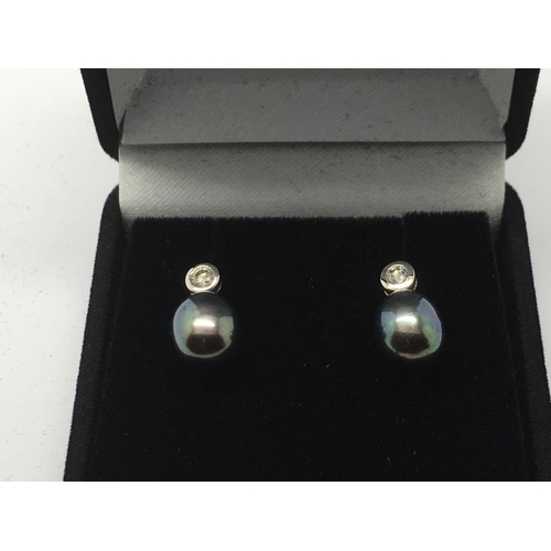 748 - A pair of 9ct white gold earrings set with a central diamond and Tahitian pearl