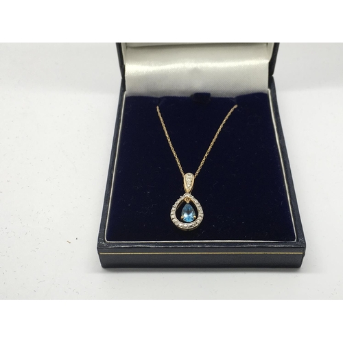 751 - A gold pendant set with a central blue topaz and diamonds on a 9ct gold chain