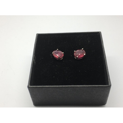 764 - A pair of silver studs set with treated rubies.