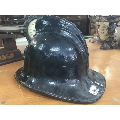 2099 - A black leather Fireman's helmet with helmet badge depicting old fire helmet