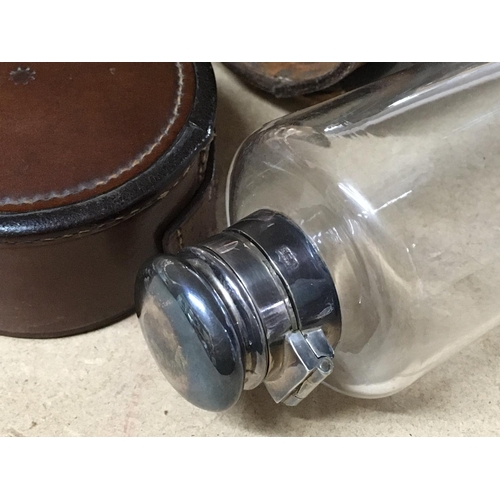 765 - A glass hip flask with silver lid inset with a leather case