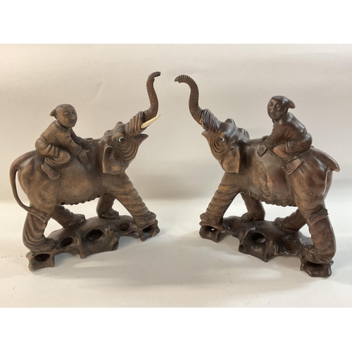 1131 - A pair of 1920s carved elephants being ridden by children.