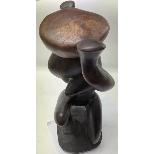 811 - A heavy shaped dark wood sculpture of a nude lady kneeling whilst holding a bowl on her head. Unattr... 