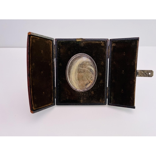 2024 - A lock of Sarianna Brownings hair in a small travelling leather picture frame. 12cm x 10cm x 2cm.