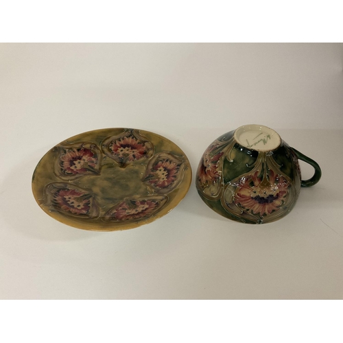 853 - A Moorcroft Pottery Cornflower design cup and saucer. (Some damage).