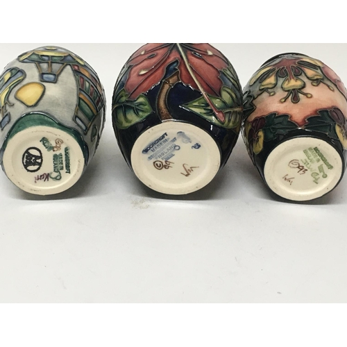 1012 - Three Moorcroft vases decorated with flowers and foliage and hot air balloons.9.5 cm and 11 cm