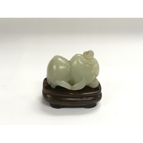 1157 - A jade figure of two peaches and a monkey raised on a hardwood stand, approx length 5cm.  NO RESERVE