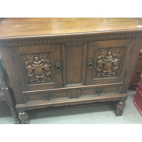 1280 - A small carved oak cabinet the cupboard doors with coats of arms above two drawers. 92x43cm NO RESER... 