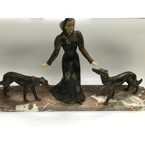 705 - An Art Deco figural group of a lady with two dogs at her side nad raised in a marble base, approx he... 