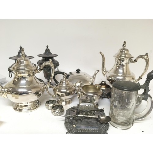 744 - A collection of silver plate tea and coffee sets a pen stand a pair of urns and covers.