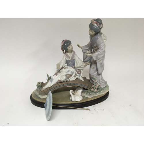 965 - A Lladro porcelain figure group depicting two Japanese women on a bridge. (Finger missing) on a hard... 