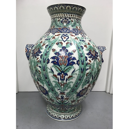 998 - A large twin handled Iznik bulbous vase decorated in traditional style, with flowers and foliage. 78... 