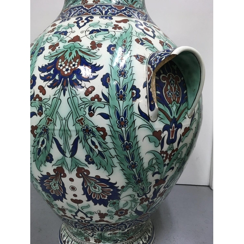 998 - A large twin handled Iznik bulbous vase decorated in traditional style, with flowers and foliage. 78... 