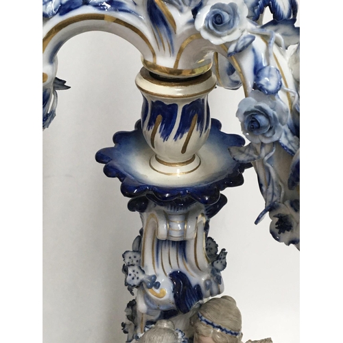 932 - A pair of Meissen candelabra with blue, white and gilt decoration o mounted with putti. 50cm. (Some ... 